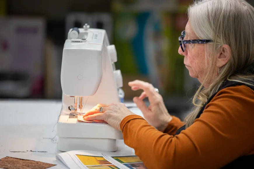Woman wearing red shirt sits at sewing machine at Richland Library