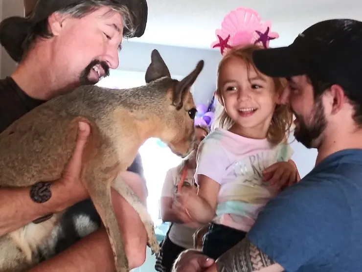 Chuck Alberding holds a baby kangaroo with a child.