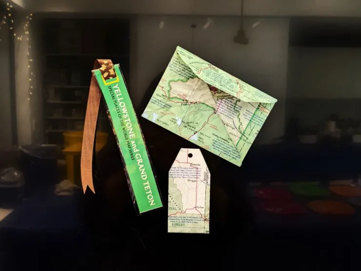 Photo: black background with three items - a bookmark with a brown ribbon, an envelope, and a gift tag - all made from various maps